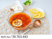 Мясная Солянка. сборная солянка. порция острого красного мясного супа с помидорами, копченостями сосисками и оливками с лимоном на светлом фоне. Стоковое фото, фотограф Оксана Медведева / Фотобанк Лори