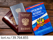 Паспорт, военный билет, трудовая книжка сотрудника и Трудовой кодекс Российской Федерации лежат на столе в отделе кадров предприятия (2023 год). Редакционное фото, фотограф Николай Винокуров / Фотобанк Лори