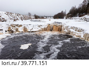 Зимний вид на долину реки и водопад. Замерзающая река. Лед и берега покрыты снегом. Холодная зимняя погода. Тосненский водопад, Река Тосна, Россия. Популярная туристическая природная достопримечательность Ленинградской области. Редакционное фото, фотограф Андрей Степанов / Фотобанк Лори