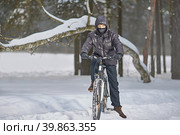 Active winter recreation. A teenager in a buff and black clothes rides a bike in winter. Стоковое фото, фотограф Кутина Татьяна / Фотобанк Лори