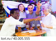 Happy multiracial friends football fans holding the flag of Russia, enjoing game and beer in the bar. Стоковое фото, фотограф Яков Филимонов / Фотобанк Лори
