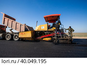 Kyzylorda province, Kazakhstan, April 29, 2012: Construction of West Europe-West China new highway. Dump truck loads asphalt in Dynapac road machine. Стоковое фото, фотограф Alexey Rezvykh / Фотобанк Лори