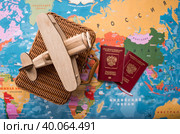 Туризм. Модель старинного самолета, чемодан и российский паспорт на фоне карты мира. Концепция путешествий, приключений и открытий. (2023 год). Стоковое фото, фотограф Photojuli / Фотобанк Лори