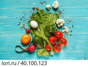 Fresh vegetables and seeds with measuring tape on aquamarine background in the center, top view. Стоковое фото, фотограф Bogdanova Mariia / Фотобанк Лори