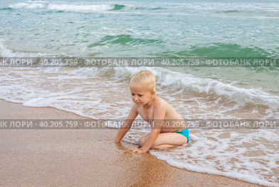 A blond boy plays in the sea wave on a sandy beach. Fun summer vacation. Стоковое фото, фотограф Коханова Наталья / Фотобанк Лори