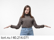 How could you. Annoyed indignant young woman spreads palms smirks face looks angrily at camera quarrels with someone feels puzzled wears jeans and sweater isolated over white background. Стоковое фото, фотограф Регина Ерофеева / Фотобанк Лори