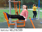 Две полные девочки тренируются на уличных тренажерах в парке одни. Стоковое фото, фотограф Vladimir Vikhrov / Фотобанк Лори