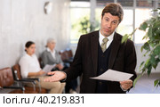 Upset businessman holding paper document in hands. Стоковое фото, фотограф Яков Филимонов / Фотобанк Лори