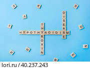 Words hypothyroidism, thyroxin and desease on wooden blocks with letters on blue background. Гормональная терапия щитовидной железы. Стоковое фото, фотограф Клара Мухаметзянова / Фотобанк Лори