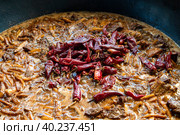 Стручки острого красного перца в кипящем мясе с овощами. Один из этапов приготовления узбекского плова. Национальная традиционная кухня Узбекистана (2022 год). Стоковое фото, фотограф Виктор Карасев / Фотобанк Лори