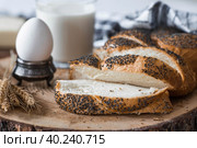 Классическая пшеничная коса или плетёнка с маком. Вкусный хлеб крупным планом. Свежеиспеченный хлеб на закваске с золотистой корочкой на деревянной доске. Контекст пекарни с вкусным хлебом. Кондитерские изделия. Стоковое фото, фотограф Photojuli / Фотобанк Лори