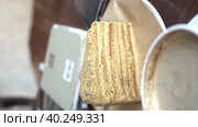 A cup of latte or cappuccino is on the table next to a sweet piece of cake. A piece of shortbread honey cake with a teaspoon on a plate near the laptop. Vertical video. Стоковое видео, видеограф Darya Komarova / Фотобанк Лори