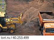 Earthworks in cramped urban conditions. The minitractor ladles the soil into the truck body. Стоковое фото, фотограф Роман Дзюбало / Фотобанк Лори
