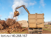 A grapple truck loads scrap industrial metal for recycling. Manipulator with a hydraulic magnetic crab against the sky. Crane garbage truck loading of industrial waste. Стоковое фото, фотограф Руслан Лесков / Фотобанк Лори