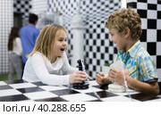 Boy adn girl solving puzzle together in room stylized like chessboard. Стоковое фото, фотограф Яков Филимонов / Фотобанк Лори