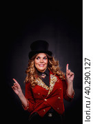 Magician woman looking up presenting show, an illusionist in circus clothes at black background, showing up index fingers. Actress lady in theatre costume. Concept of stage fun perform. Copy ad space. Стоковое фото, фотограф Aleksandr Golubev / Фотобанк Лори