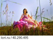 Beautiful girl in a lush pink ball gown in green field during blooming of flowers and blue sky on background. Model posing on nature landscape as princess from fary tale. Стоковое фото, фотограф Кривошеина Елена Леонидовна / Фотобанк Лори