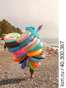 A seller with a bunch of different rubber rings strolls along the beach. Стоковое фото, фотограф Татьяна Дворецкая / Фотобанк Лори