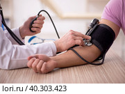 Old male doctor measuring young patient's blood pressure. Стоковое фото, фотограф Elnur / Фотобанк Лори