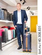 Positive man chose suitcase in haberdashery store. Стоковое фото, фотограф Яков Филимонов / Фотобанк Лори