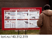 Охранник читает информацию у стенда по антитеррористической безопасности в Парке Горького в городе Москве, Россия (2023 год). Редакционное фото, фотограф Николай Винокуров / Фотобанк Лори