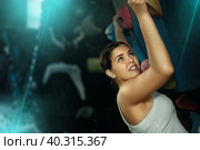 Female fitness climber training at bouldering gym. Young woman rise up on artificial climbing wall. Стоковое фото, фотограф Яков Филимонов / Фотобанк Лори