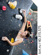 Female fitness climber training at bouldering gym. Young woman rise up on artificial climbing wall. Стоковое фото, фотограф Яков Филимонов / Фотобанк Лори