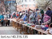 Russia, the City of Vidnoye, April 15, 2023. Easter service. The priest sprinkles people and Easter treats with holy water at the entrance to the temple. People go to sanctify eggs and cakes. Редакционное фото, фотограф Photojuli / Фотобанк Лори