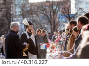 Russia, the City of Vidnoye, April 15, 2023. Easter service. The priest sprinkles people and Easter treats with holy water at the entrance to the temple. People go to sanctify eggs and cakes. Редакционное фото, фотограф Photojuli / Фотобанк Лори