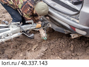 A man checking the hitch mechanism on a car trailer in bad weather. Стоковое фото, фотограф Коханова Наталья / Фотобанк Лори