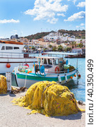 Greece. Crete. Marina of Elounda with traditional Greek fishing boats and yellow fishing nets on pier against background of town with white houses on hill on sunny day. Beautiful seascape. Summer seaside rest (2014 год). Стоковое фото, фотограф Виктория Катьянова / Фотобанк Лори