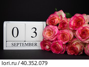 September 3 wooden calendar, white on a black background, pink roses lie nearby. Стоковое фото, фотограф Anna Scherbina / Фотобанк Лори