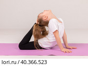 Happy little girl doing gymnastics isolated on white background. Стоковое фото, фотограф Ирина Михайличенко / Фотобанк Лори