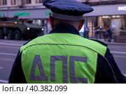 Сотрудник ДПС стоит на посту на Тверской улице в центре города Москвы и обеспечивают безопасность движения на дороге во время прохода колонны военной техники, Россия (2023 год). Редакционное фото, фотограф Николай Винокуров / Фотобанк Лори