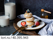 Cottage cheese pancakes, Russian cheesecakes with fresh blueberries, strawberries, honey and mint leaves on a stylish wooden board on a dark background. Natural products. Healthy and delicious breakfast. Стоковое фото, фотограф Photojuli / Фотобанк Лори