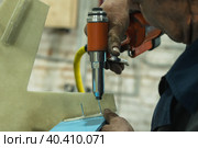A man's hand uses a pneumatic tool to fasten parts. Riveting gun. Close-up. A worker in a pedal catamaran assembly shop. Стоковое фото, фотограф Воловодов Владимир / Фотобанк Лори
