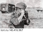 Неизвестный участник исторической реконструкции в форме немецкой армии с ретро-камерой в летний день (2017 год). Редакционное фото, фотограф FotograFF / Фотобанк Лори