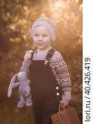 A little boy of 4 years old outdoors with a suitcase and a stuffed rabbit goes on a journey. A beautiful portrait of a child playing on the street. Стоковое фото, фотограф Photojuli / Фотобанк Лори