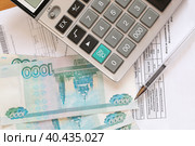Концепция оплаты коммунальных услуг-  российские рубли, калькулятор на фоне счетов за услуги. Стоковое фото, фотограф Римма Тельнова / Фотобанк Лори