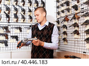 Man examining sporting revolvers before buying in gun store. Стоковое фото, фотограф Яков Филимонов / Фотобанк Лори