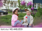 Lifestyle. Little beautiful children are playing on a bench with candy lollipops on a stick in the shape of a heart. The concept of childhood friendship and first love. Стоковое фото, фотограф Photojuli / Фотобанк Лори