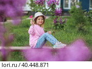 Lifestyle. A beautiful little girl in pink clothes with a lollipop in the shape of a heart. The girl licks the candy. The concept of love and sweets. Стоковое фото, фотограф Photojuli / Фотобанк Лори