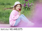 Lifestyle. A beautiful little girl in pink clothes with a lollipop in the shape of a heart. The girl licks the candy. The concept of love and sweets. Стоковое фото, фотограф Photojuli / Фотобанк Лори