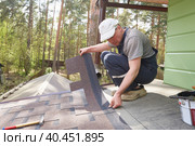 A man lays a roof of soft tiles on the roof of a country house. Стоковое фото, фотограф Кутина Татьяна / Фотобанк Лори
