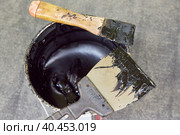 Black mastic in a jar with spatulas. Waterproofing. Waterproofing insulation of a roof. Стоковое фото, фотограф Кутина Татьяна / Фотобанк Лори