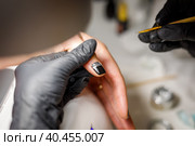 In the beauty studio, the master does a manicure, applies a pattern to the nail with a brush. Стоковое фото, фотограф Юрий Поздников / Фотобанк Лори
