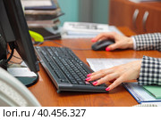 A woman director working in an office is sitting at a table, typing on a keyboard, checking documents. Стоковое фото, фотограф Юрий Поздников / Фотобанк Лори