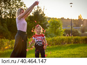 Mom plays with her daughter in the park, sprinkles autumn leaves on top. Russia Moscow September 24, 2020. Редакционное фото, фотограф Юрий Поздников / Фотобанк Лори