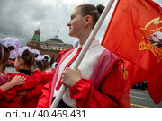 Девушка держит красный флаг с эмблемой Пионерской организации на торжественной линейке, посвященной приему в пионеры на Красной площади города Москвы, Россия (2023 год). Редакционное фото, фотограф Николай Винокуров / Фотобанк Лори