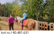 На улице в прекрасный теплый день девочка катается на лошади. Outside on a beautiful warm day, a girl rides a horse. Редакционное видео, видеограф Мария / Фотобанк Лори